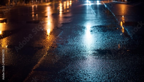 A dark, rainy night with reflections of streetlights on wet pavement © kimberly