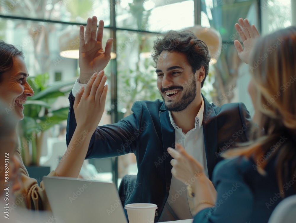 A group of professional adults celebrate in a friendly office environment, with one man and one woman giving each other a high-five. A group of professional adults celebrate in a friendly office environment, with one man and one woman giving each other a high-five.