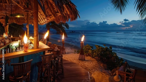 Tropical beach bar at sunset with tiki torches and ocean views. photo