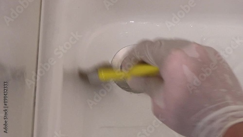 Close up view of painting shower floor with a brush in the bathroom.
