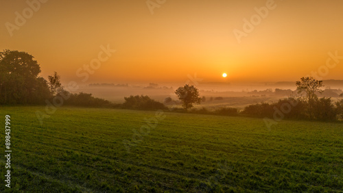 Bocage normand baignant dans une lumière jaune orange rouge sous le soleil levant