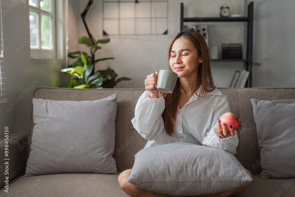 Woman Relaxing in the Morning with Coffee and Fruit in a Cozy Modern Living Room Woman Relaxing in the Morning with Coffee and Fruit in a Cozy Modern Living Room