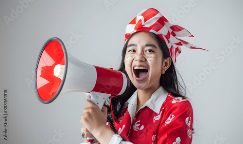 Asian person wearing red white flag ribborn and megaphone for indonesia independence photo