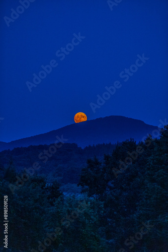 The full flower moon -  07, 2024. The rising moon over the mountain peaks , a cloudless night allows observation of the astronomical phenomenon. 