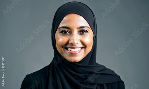 portrait of beautiful muslim woman in hijab smiling on grey background