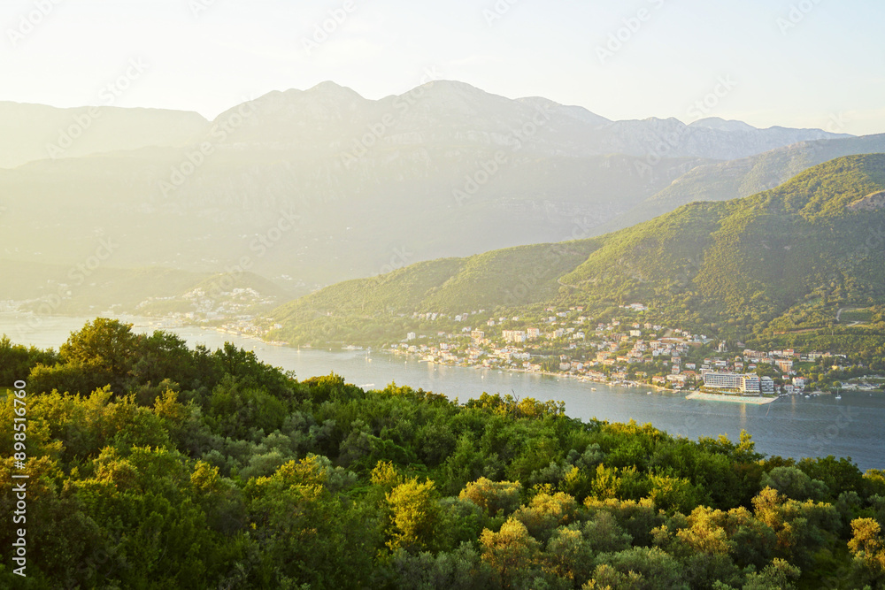 Naklejka premium Summer sunset in the municipality of Herceg Novi: view of the mountains, sea, forest and coastal settlements painted in golden rays of the sun. Evening landscape from the Bay of Kotor, Montenegro.