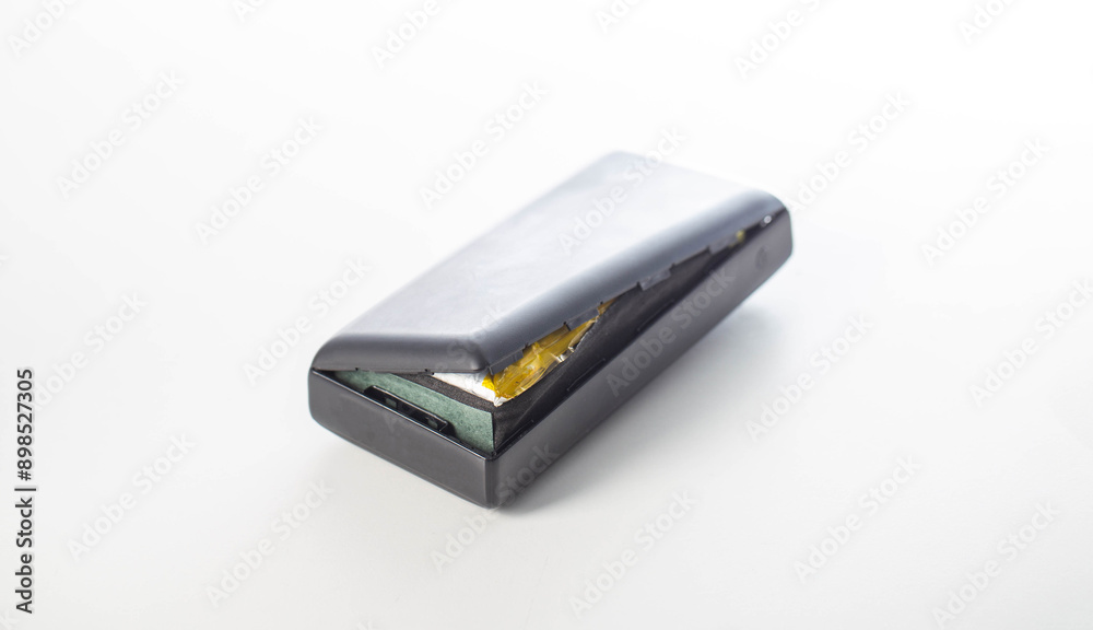 Bloated black power bank on a white background, isolate. Danger of power bank explosion, close-up Bloated black power bank on a white background, isolate. Danger of power bank explosion, close-up