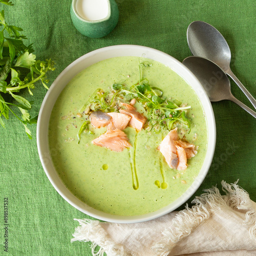 bowl with creamy soup of zucchini, broccoli and salmon on the table
