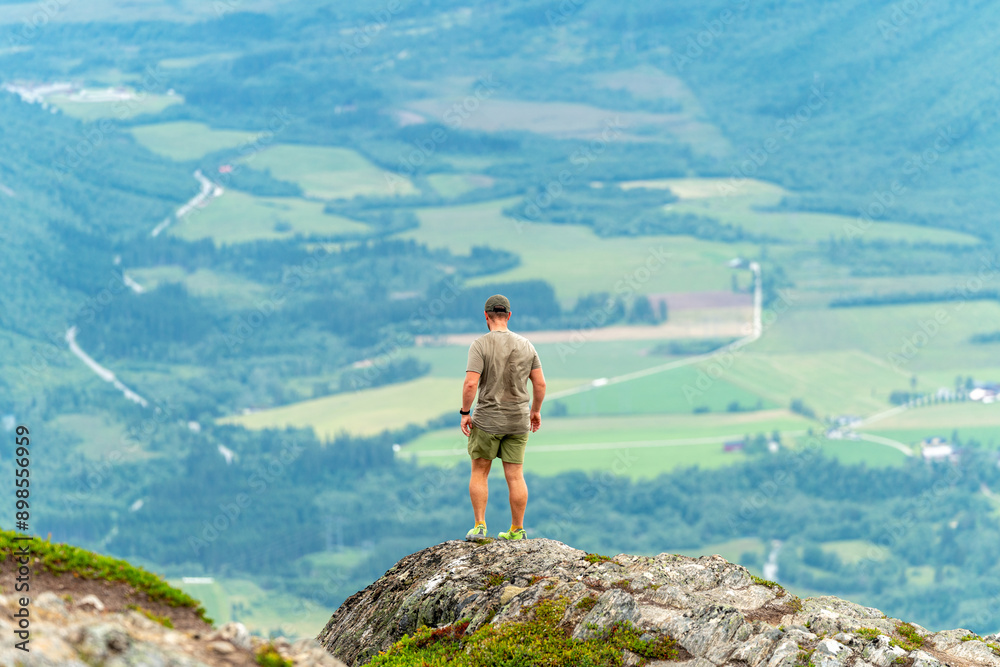 Obraz premium male backpacking hiker with yellow backpack climbing Romsdalseggen trail in Andalsnes Norway in summer with rocky mountains in the background