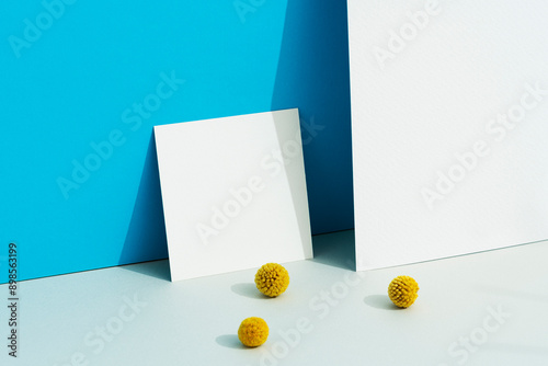 White blank square paper mockup on blue background with billy buttons photo