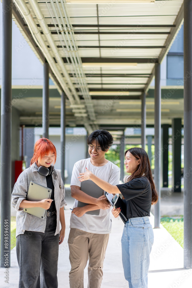 Obraz premium Three young people are walking down a hallway, each carrying a laptop