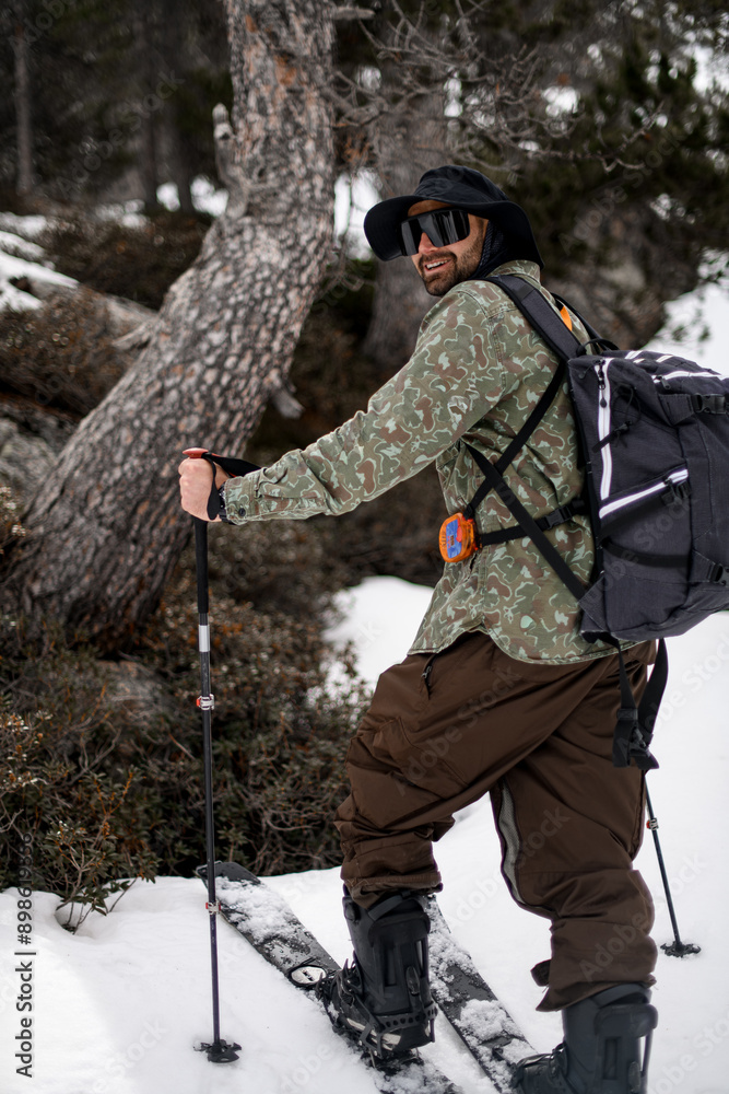 Smiling skier in glasses and a wide black hat is turned sideways and into the distance Smiling skier in glasses and a wide black hat is turned sideways and into the distance
