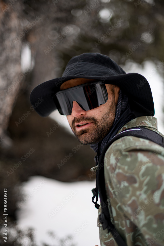 Focus on the face of a skier in glasses and a wide black hat, standing Focus on the face of a skier in glasses and a wide black hat, standing