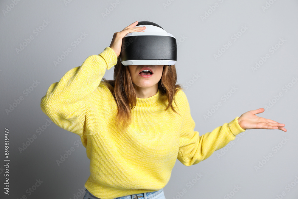 Surprised woman using virtual reality headset on light grey background Surprised woman using virtual reality headset on light grey background