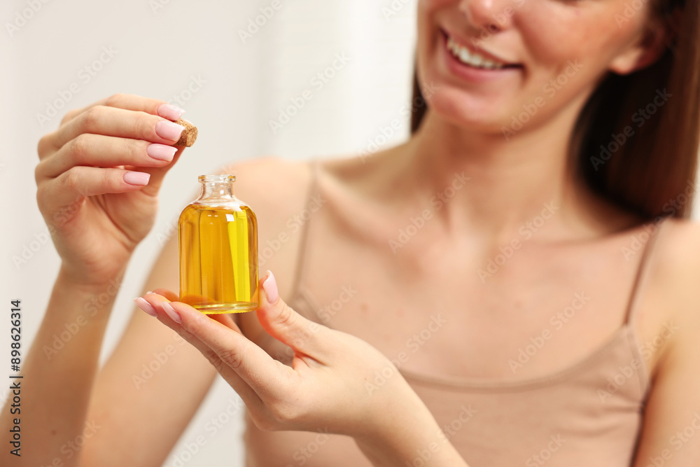 Fototapeta premium Aromatherapy. Woman with bottle of essential oil on light background, closeup