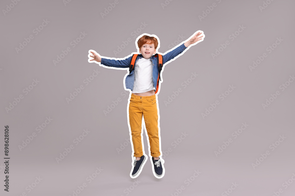 Happy school child with backpack jumping on grey background Happy school child with backpack jumping on grey background
