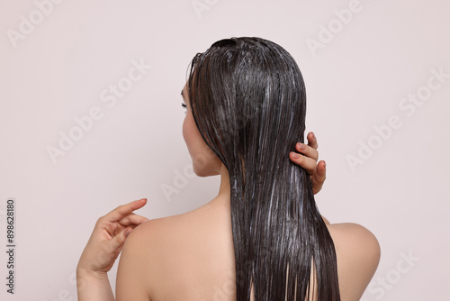 Quadro su tela Woman applying hair mask on light background, back view