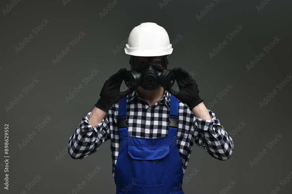 Fototapeta premium Worker in gas mask and helmet on grey background