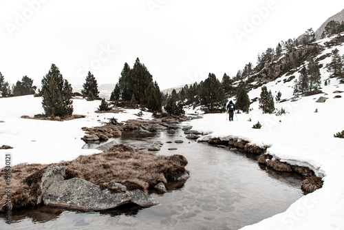 In the foreground is a mountain stream with transparent clean water, past which a skier goes