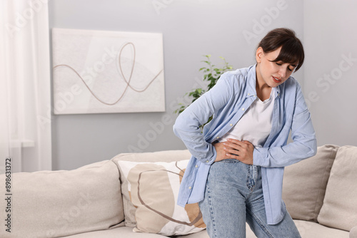 Tablou pe pânză Upset woman suffering from abdominal pain at home, space for text