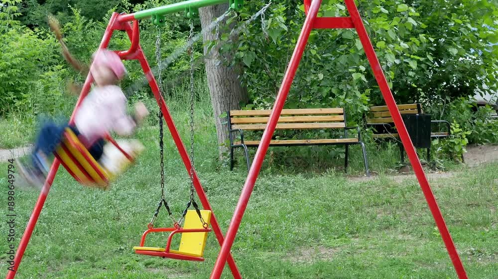 A little girl is quickly swinging on a swing in an outdoor playground. A little girl is quickly swinging on a swing in an outdoor playground.