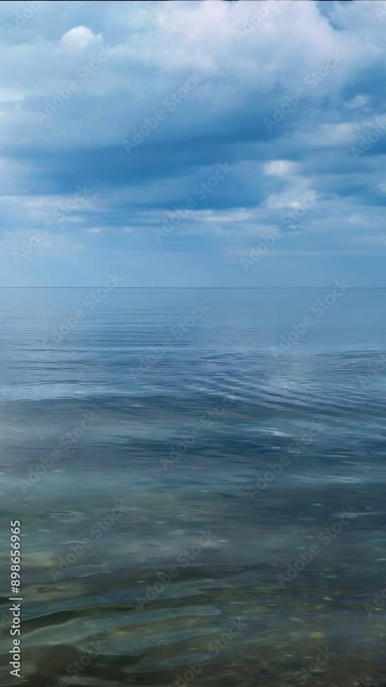 Vertical panoramic video of serene seascape with dramatic cloudy sky reflected in mirror water surface of calm sea at fine summer day. With no people beautiful natural background animation. Vertical panoramic video of serene seascape with dramatic cloudy sky reflected in mirror water surface of calm sea at fine summer day. With no people beautiful natural background animation.