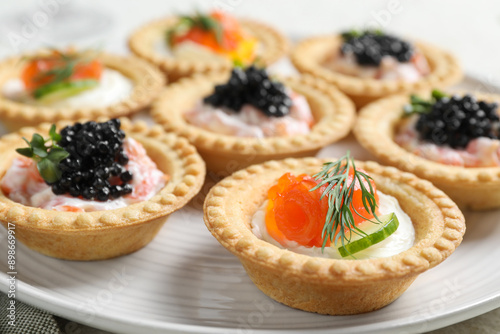 Delicious canapes with salmon and caviar on plate, closeup