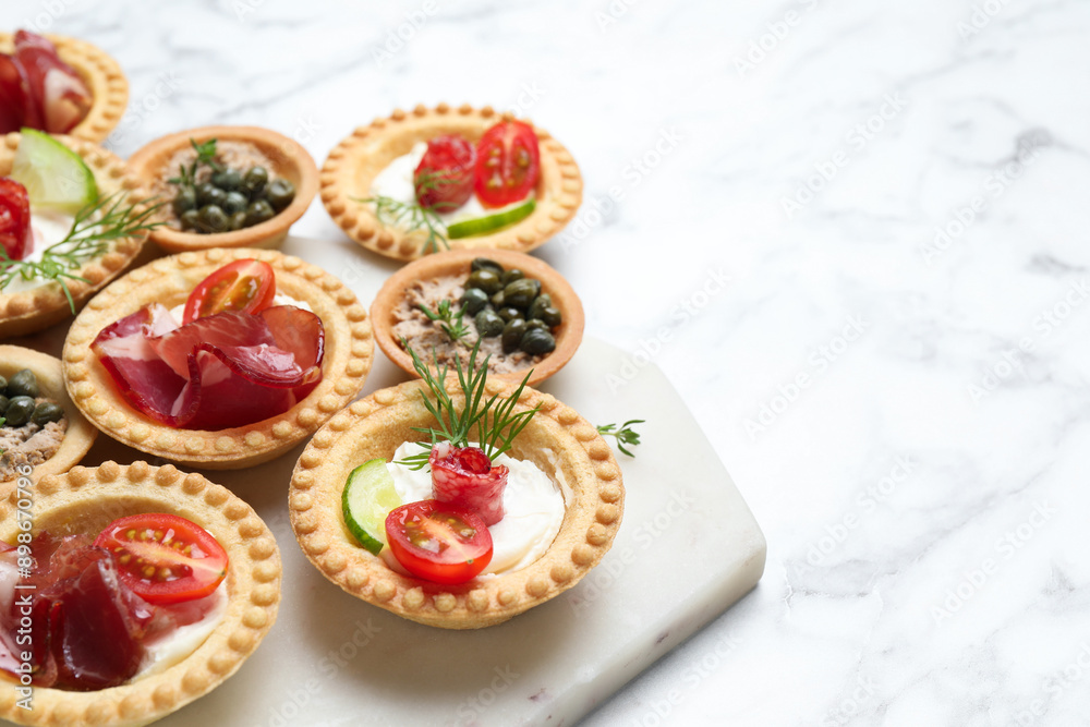 Different delicious canapes on white marble table, space for text