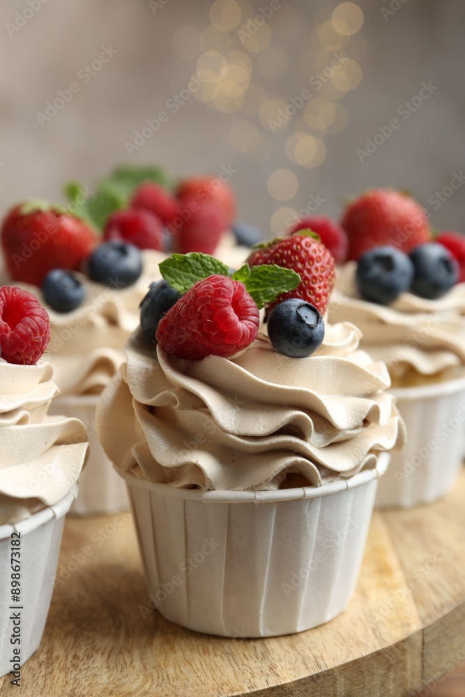 Tasty cupcakes with different berries and mint on wooden table, closeup Tasty cupcakes with different berries and mint on wooden table, closeup