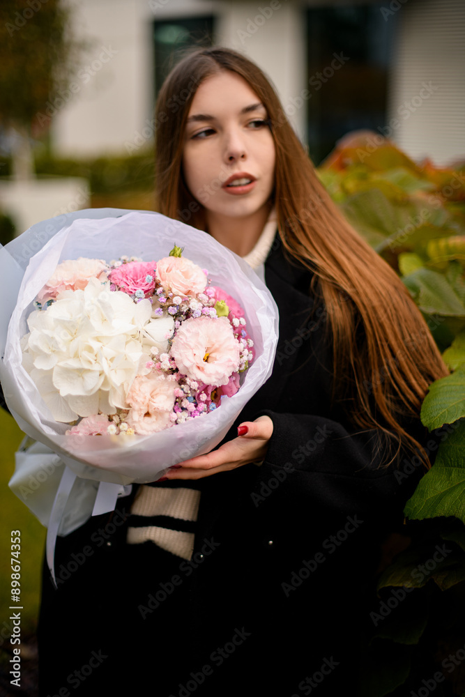 Fototapeta premium Pretty young woman neatly holding a delicate bouquet of various pink and white flowers