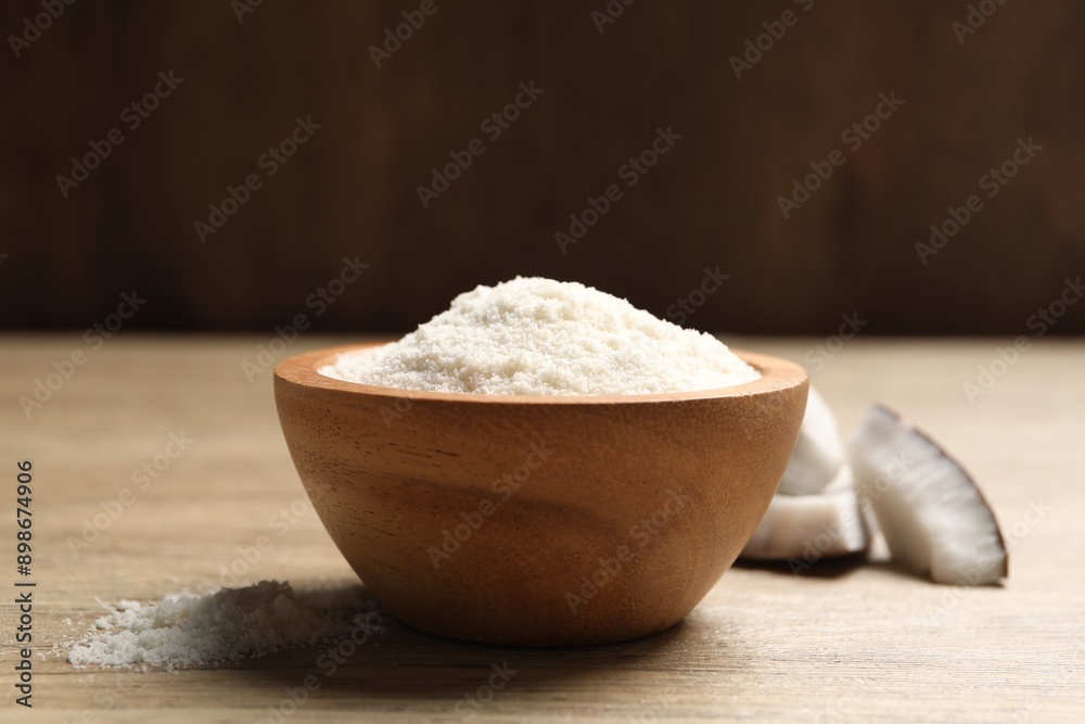 Fresh coconut flour in bowl and nut on wooden table Fresh coconut flour in bowl and nut on wooden table