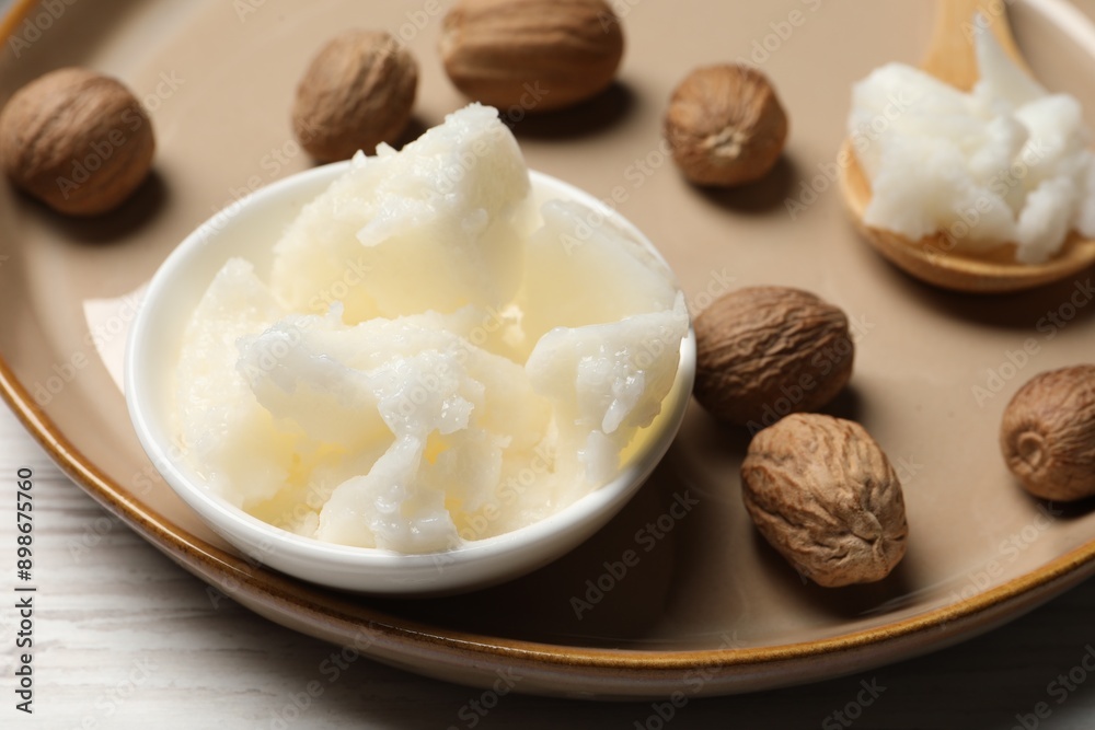 Natural shea butter in bowl and nuts on wooden table, closeup Natural shea butter in bowl and nuts on wooden table, closeup