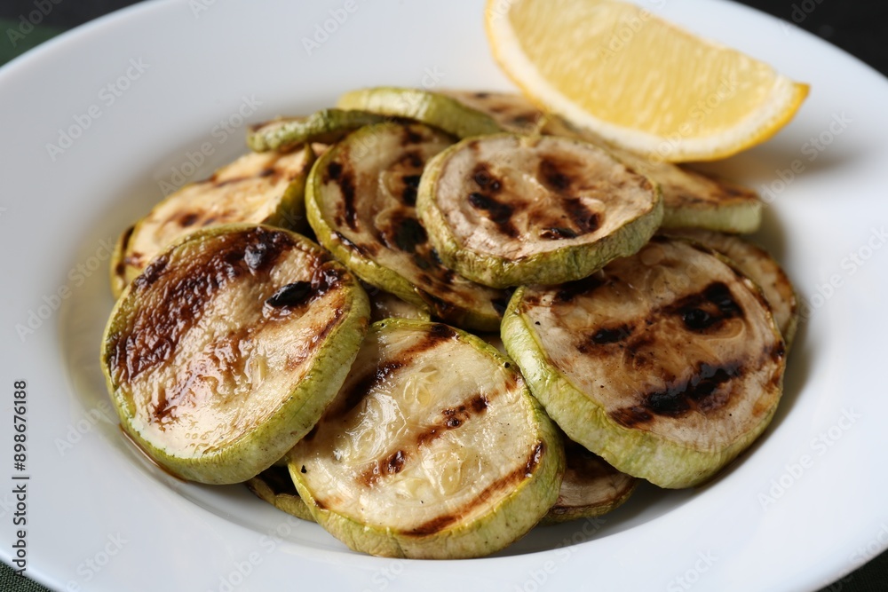 Tasty grilled zucchini slices with lemon on black table, closeup Tasty grilled zucchini slices with lemon on black table, closeup