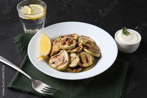 Tasty grilled zucchini slices served on black table
