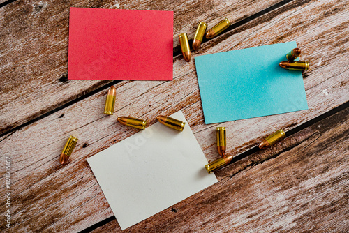 red blue and white empty notes with scattered 9 mm bullet ammunition on wood plank background photo