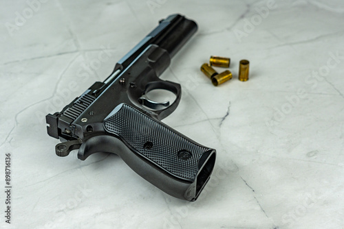 black pistol gun with shells on empty white marble background