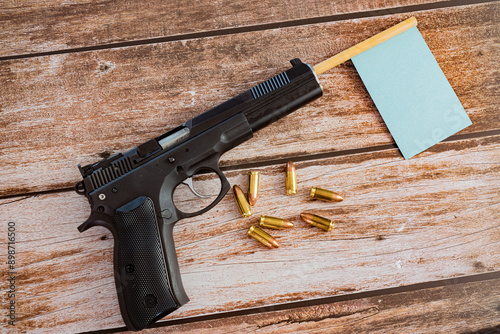 blue flag out of black pistol gun barrel with bullets on wooden plank background