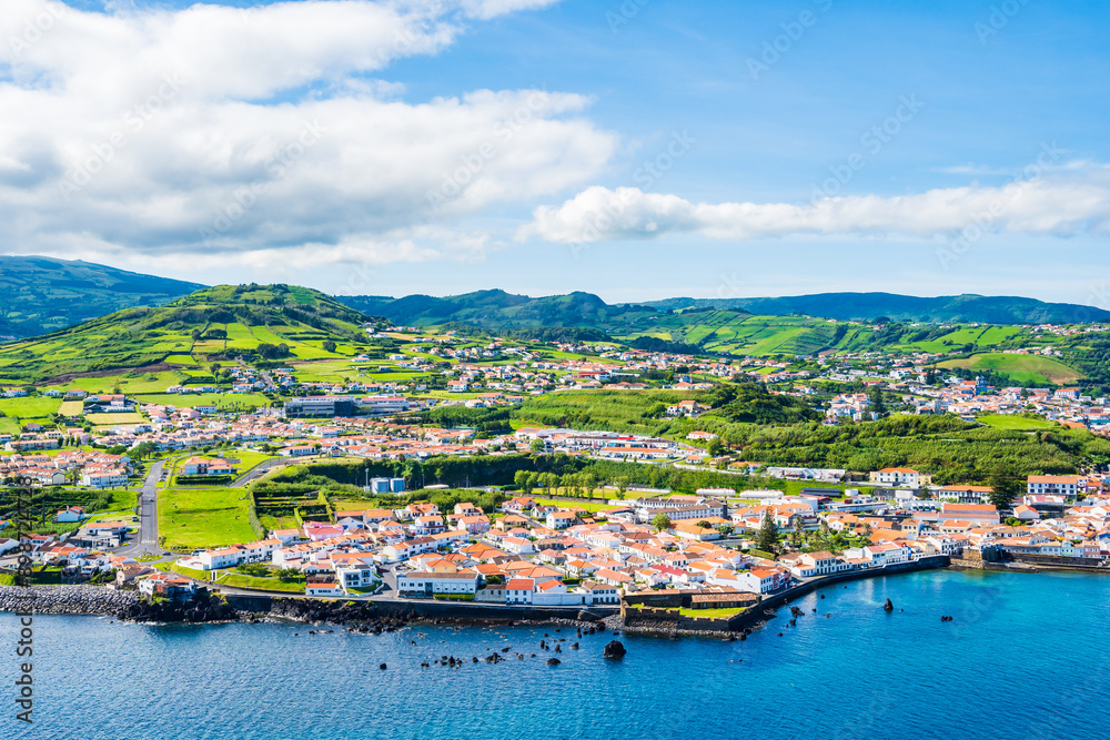 Obraz premium View of Horta town on ocean coast with green farming hills in background, Faial island, Azores, Portugal