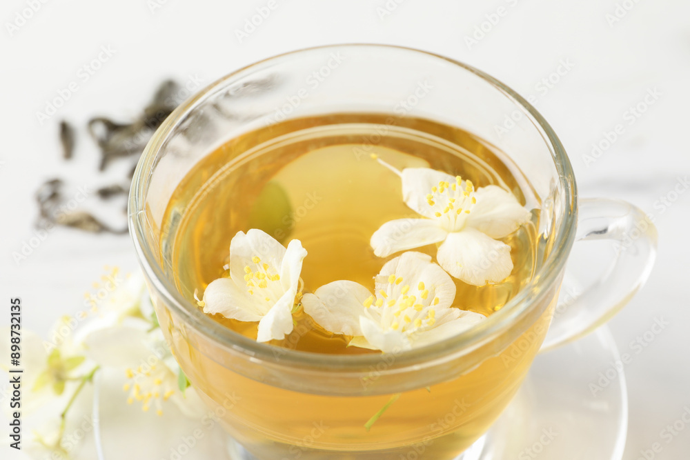 Aromatic jasmine tea in cup and flowers on table, closeup Aromatic jasmine tea in cup and flowers on table, closeup