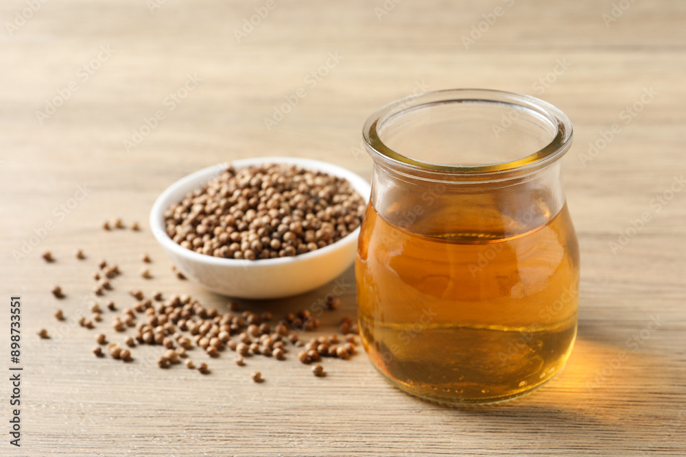 Fototapeta premium Dried coriander seeds in bowl and oil on wooden table