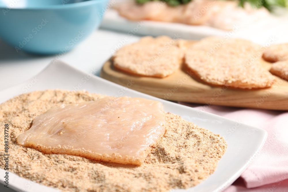 Making schnitzels. Raw meat with bread crumbs on table, closeup Making schnitzels. Raw meat with bread crumbs on table, closeup