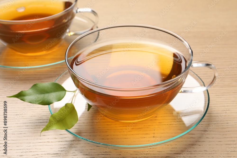 Refreshing green tea in cups and leaves on wooden table, closeup Refreshing green tea in cups and leaves on wooden table, closeup