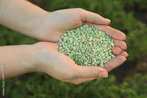 Woman holding green plant fertilizer outdoors, closeup © New Africa