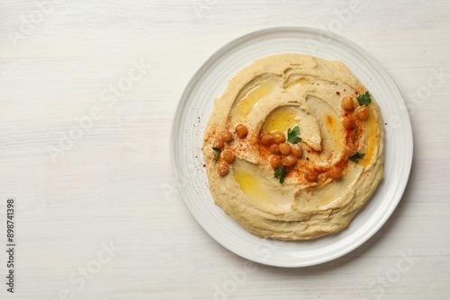 Delicious hummus with olive oil, chickpeas and paprika on white wooden table, top view. Space for text