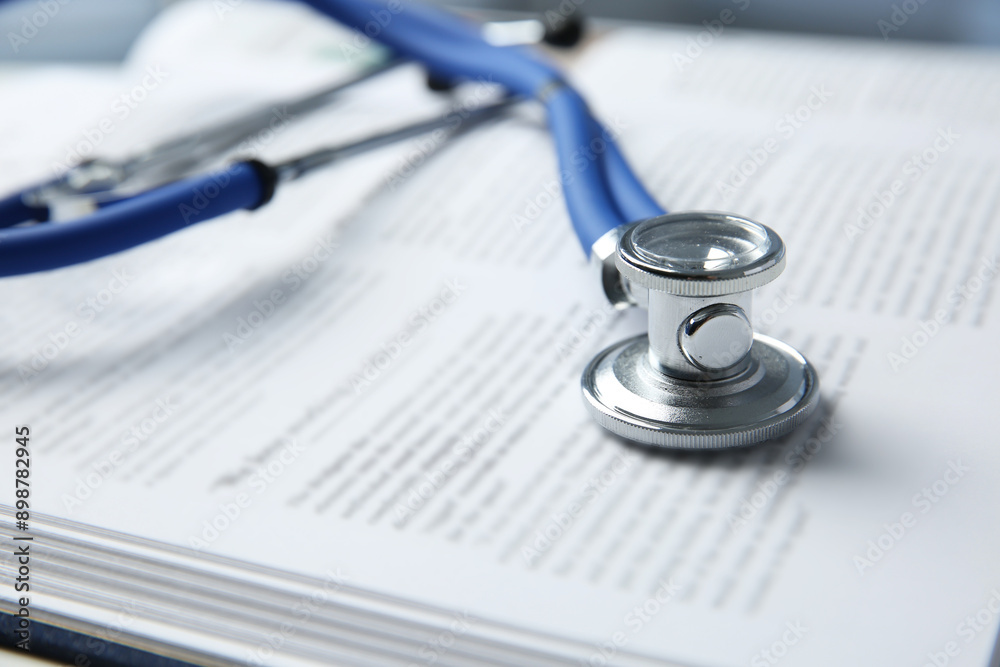 One medical stethoscope and book on table, closeup One medical stethoscope and book on table, closeup
