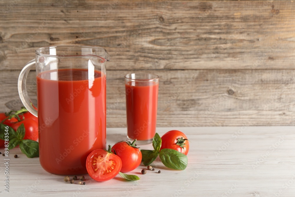 Tasty tomato juice in jug, basil, peppercorns and vegetables on light wooden table indoors. Space for text Tasty tomato juice in jug, basil, peppercorns and vegetables on light wooden table indoors. Space for text