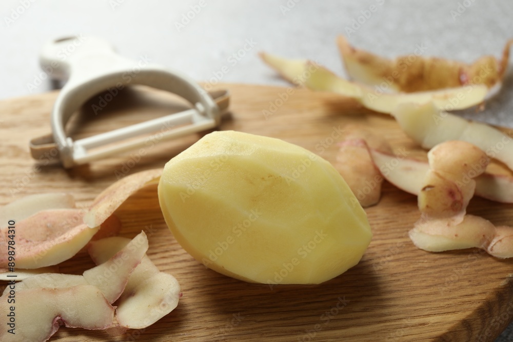 Fresh raw potato, peels and peeler on table, closeup Fresh raw potato, peels and peeler on table, closeup