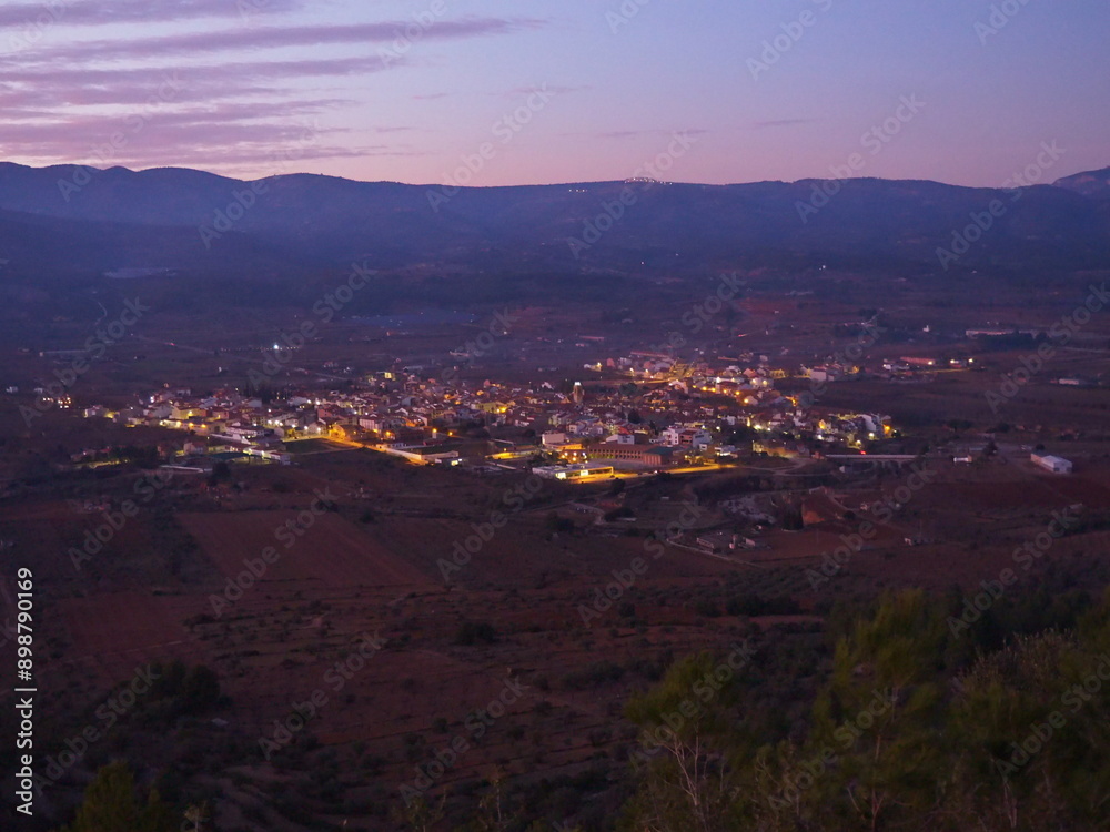 Obraz premium Adzaneta del Maestre, a village in El Maestrazgo, in the Province of Castellón, Spain, illuminated at night, from the mountains of El Bovalar