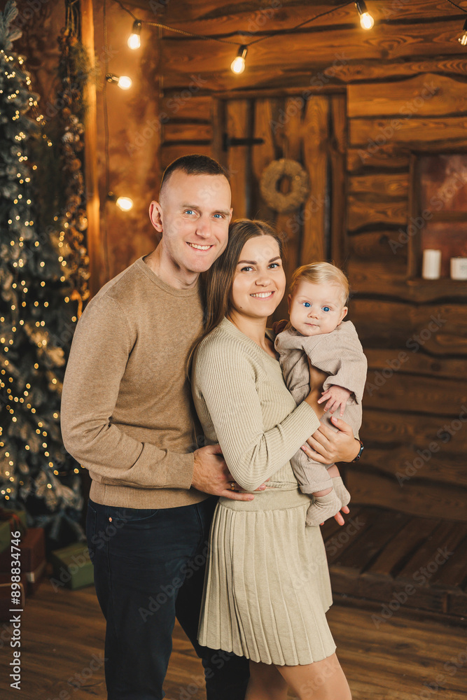 A happy family couple with a child in their arms on the background of a Christmas tree. New Year with a baby. Family New Year's atmosphere. A happy family couple with a child in their arms on the background of a Christmas tree. New Year with a baby. Family New Year's atmosphere.