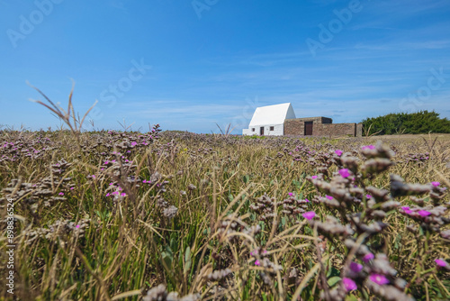 Low angle view of Le Don Hilton, known as the white house, is an old guard house at the centre of St Ouen's Bay, Jersey, Channel Islands. Built in 1765 as a guardhouse magazine, it is protected under 